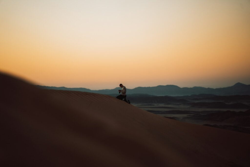 a person sitting on top of a sand dune